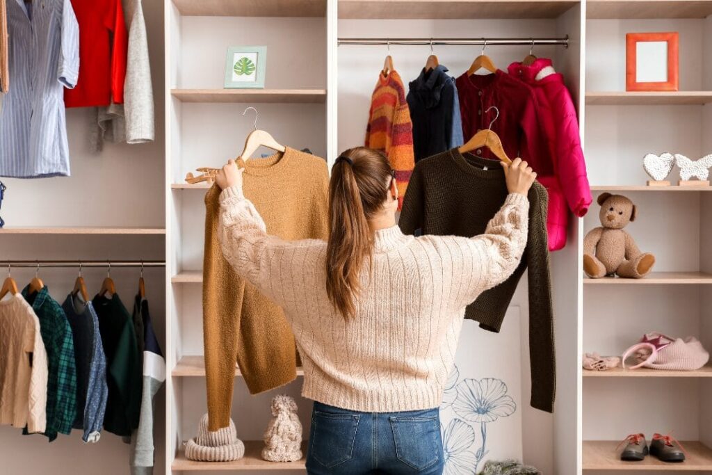 Donna di spalle che sistema i vestiti in una cabina armadio a vista