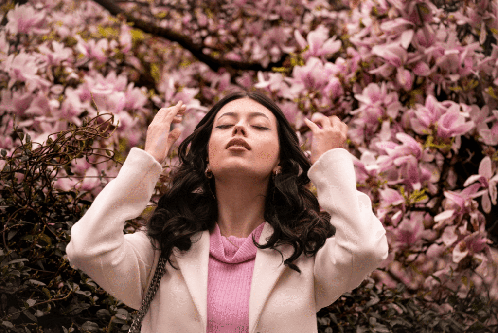 Donna con giacca rosa cipria tra i rami di ciliegio in fiore